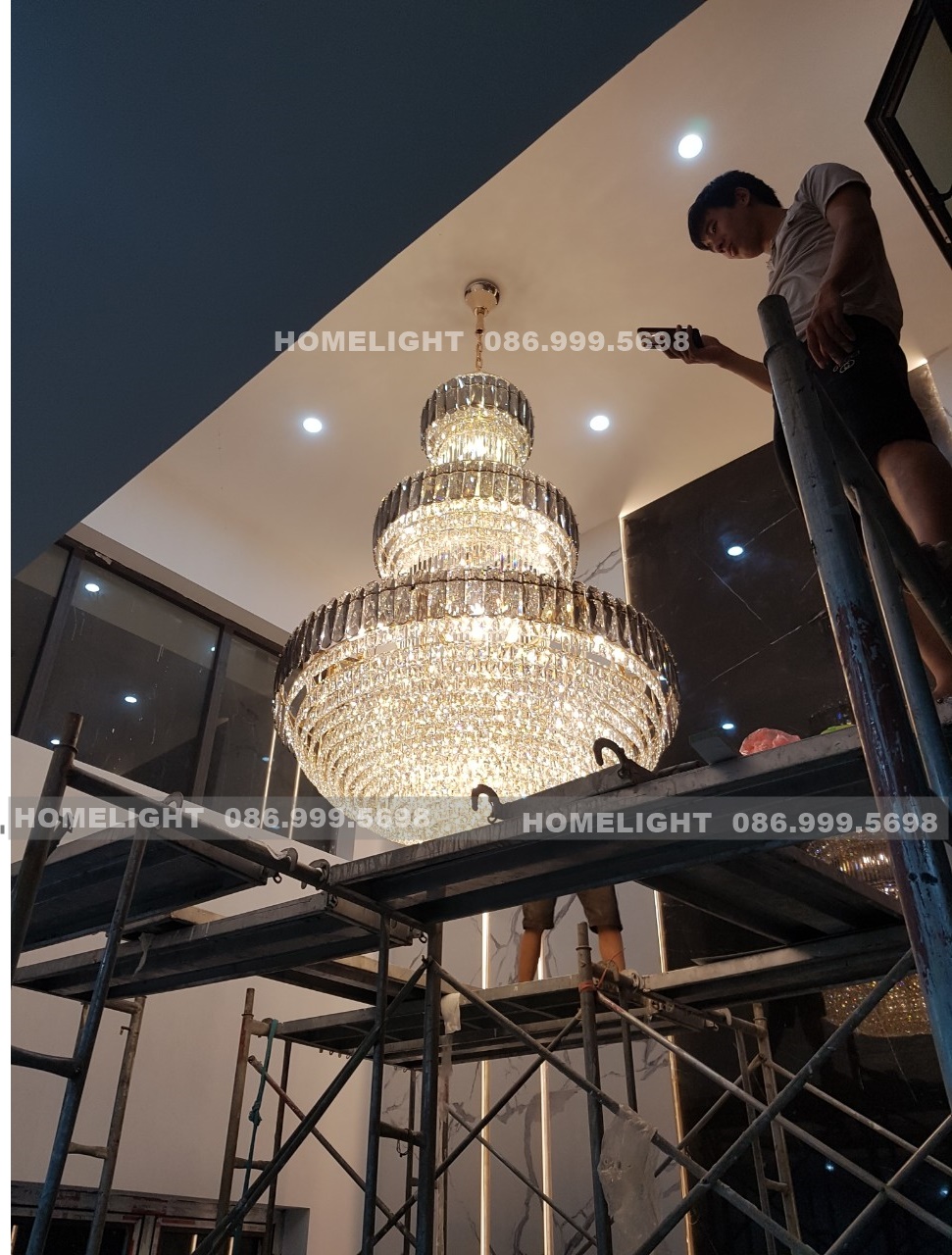 Đèn chùm thông tầng pha lê sáng đèn lần đầu, thợ HomeLight kiểm tra trên giàn giáo tại Villa Thạch Thất